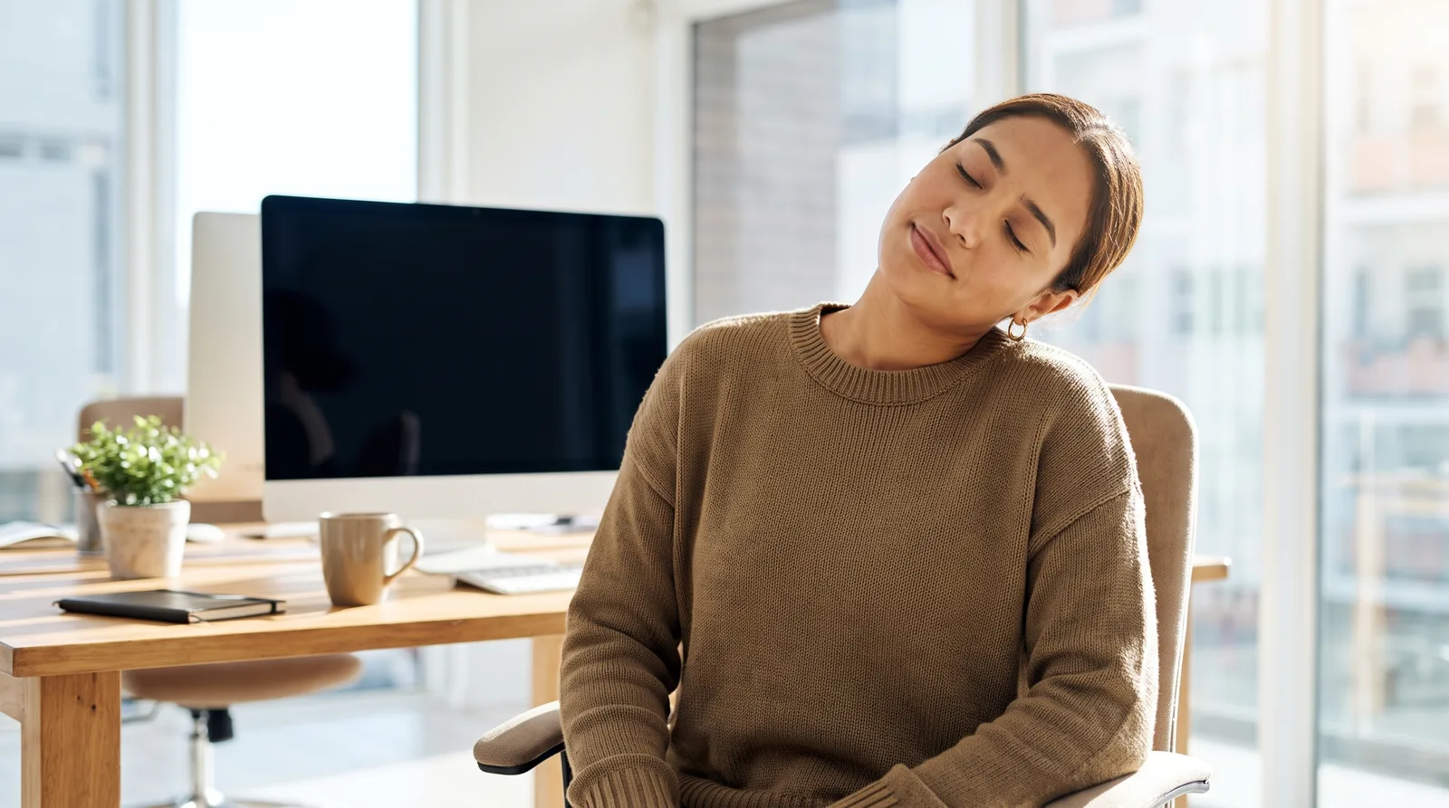 Una persona en su escritorio realizando un movimiento de cuello suave y controlado durante una pausa laboral