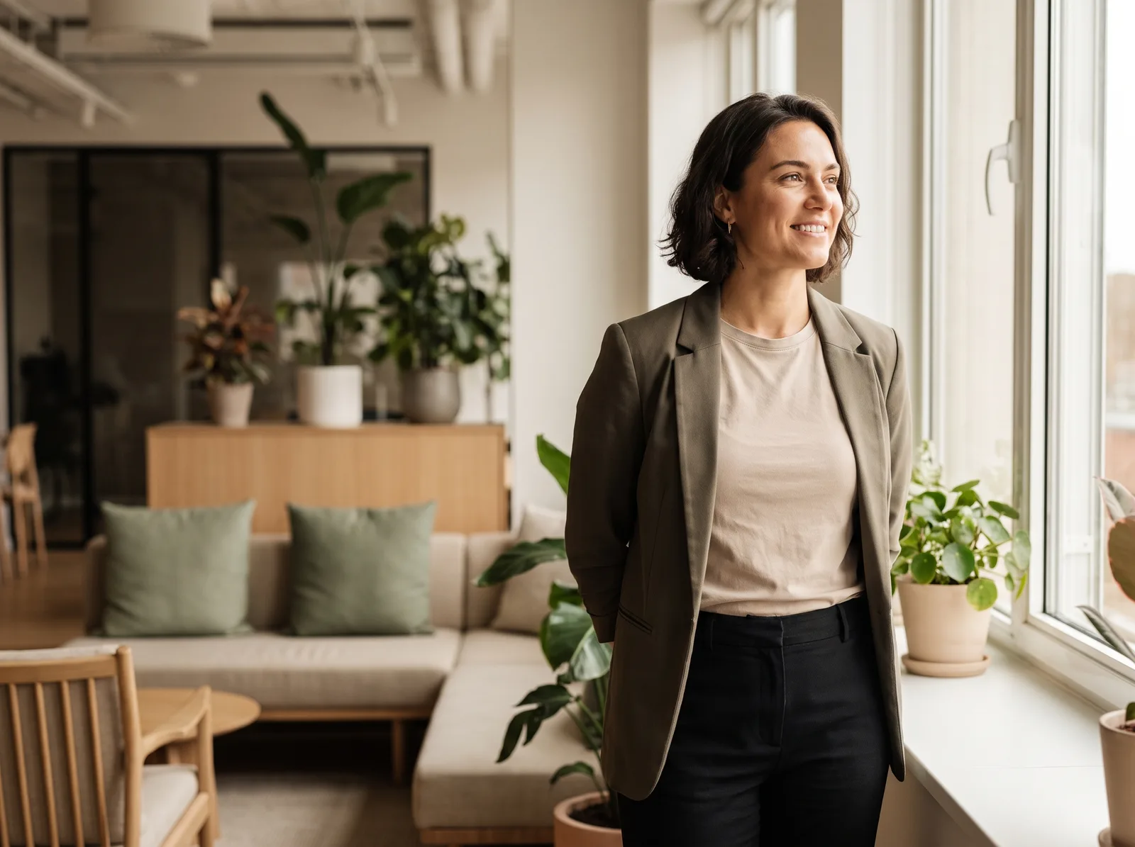 A person standing tall with relaxed, confident, open posture in a bright office
